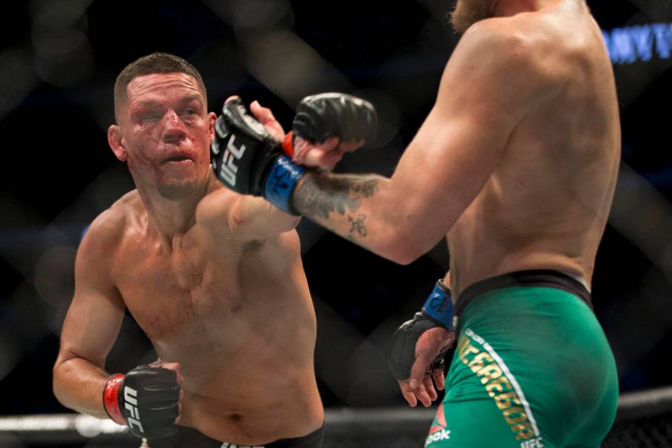 Nate Diaz, left, throws a punch against Conor McGregor in the welterweight bout during UFC 202 ...