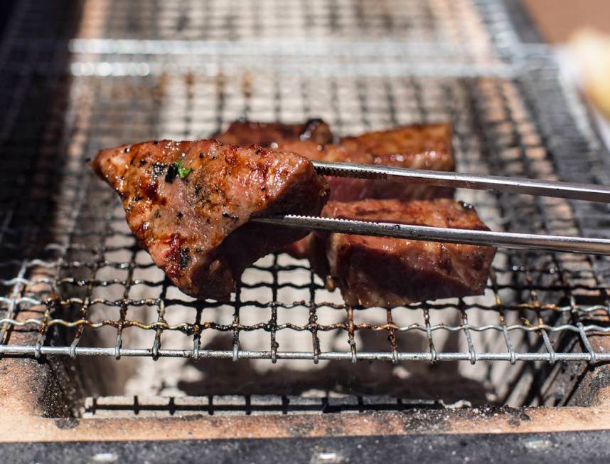 Aged beef cooks on a robata grill in the backyard of John Courtney, chef of Block 16 at The Cos ...