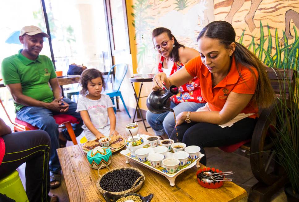 Gio Marongiu, store manager at Java Tree, right, pours coffee in a traditional Ethiopian coffee ...