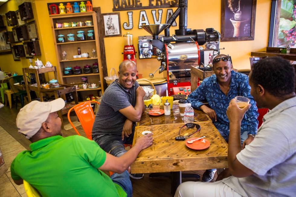 Solomon Teklu, owner of Java Tree, left, talks with his customers including Mekonnen Gebremedhi ...