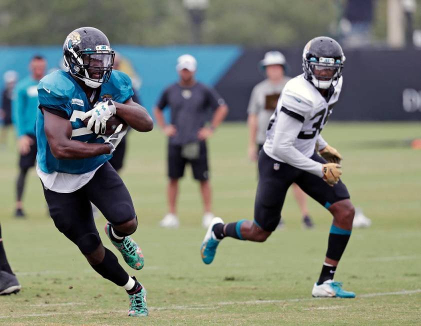 Jacksonville Jaguars running back Leonard Fournette, left, runs for yardage past cornerback Sai ...