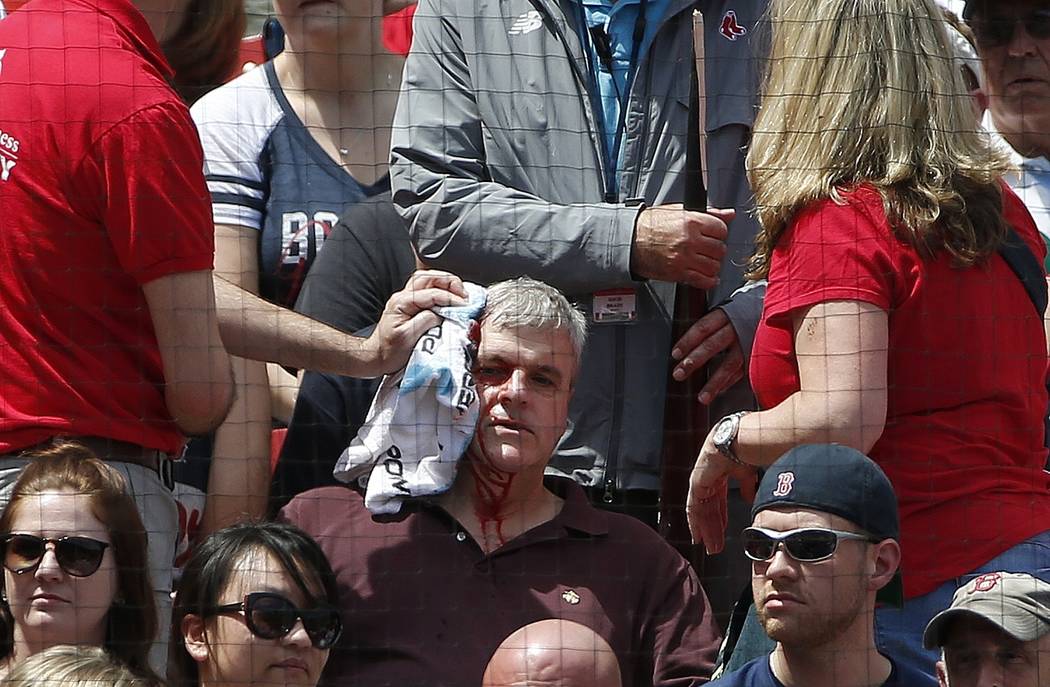 Fenway Park personnel attend to a fan who was hit by a broken bat during the first inning of a ...