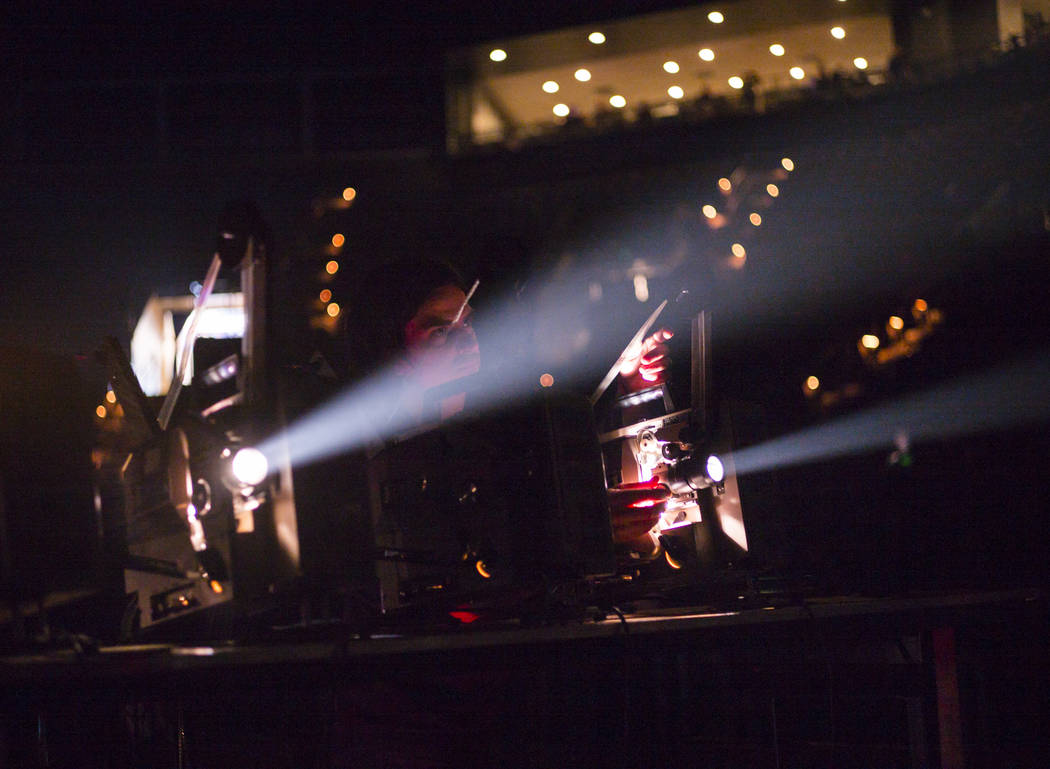 A technician projects lights onto the screen as Godspeed You! Black Emperor performs at the Man ...