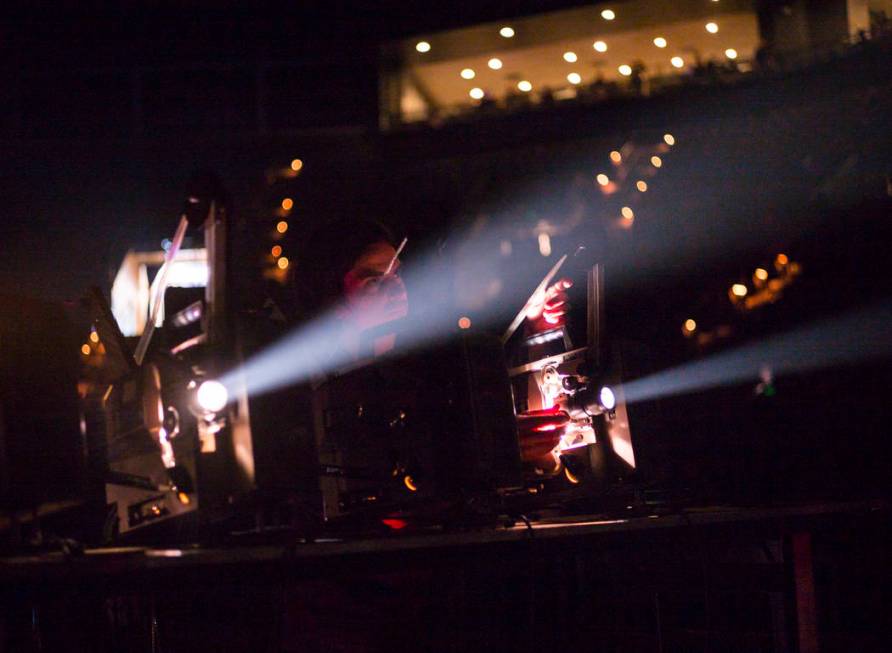 A technician projects lights onto the screen as Godspeed You! Black Emperor performs at the Man ...