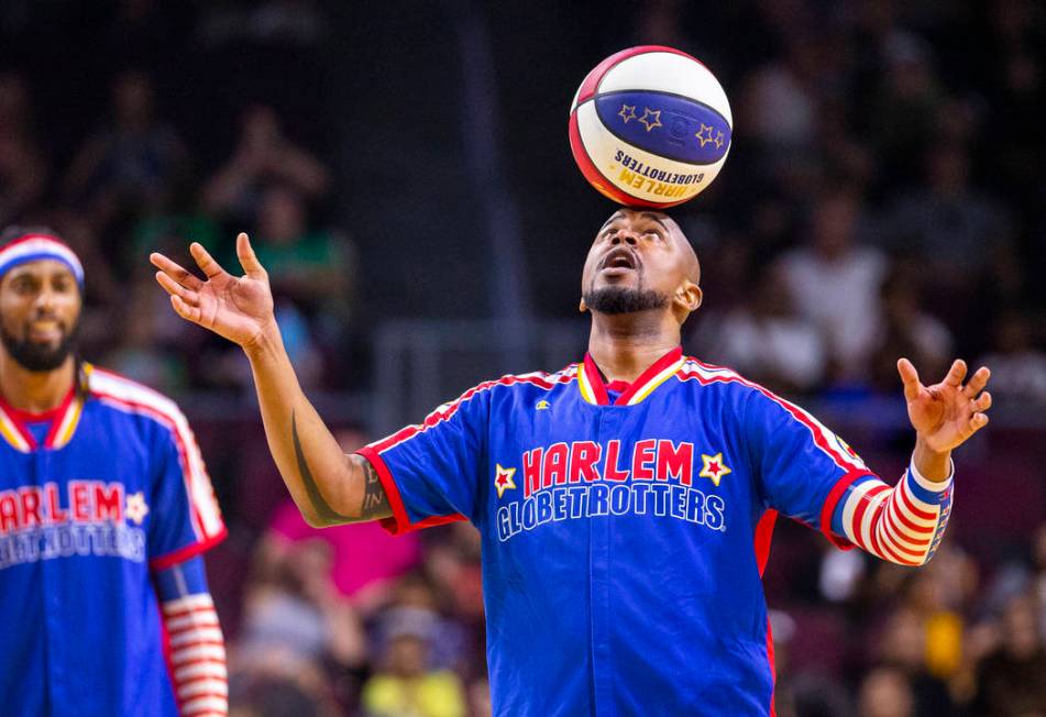 Harlem Globetrotter Scooter Christensen (16) balances a basketball on his head as the team show ...