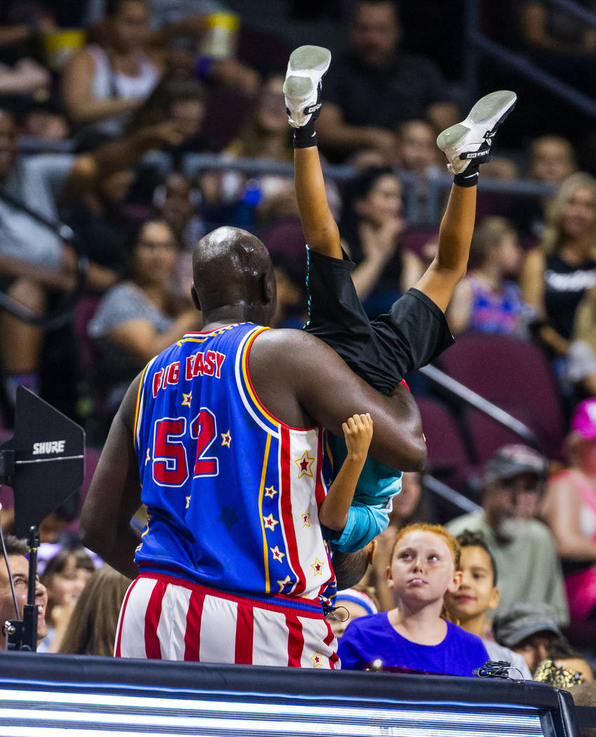 Harlem Globetrotter Big Easy Lofton (52) carries a young fan to his parents while joking around ...