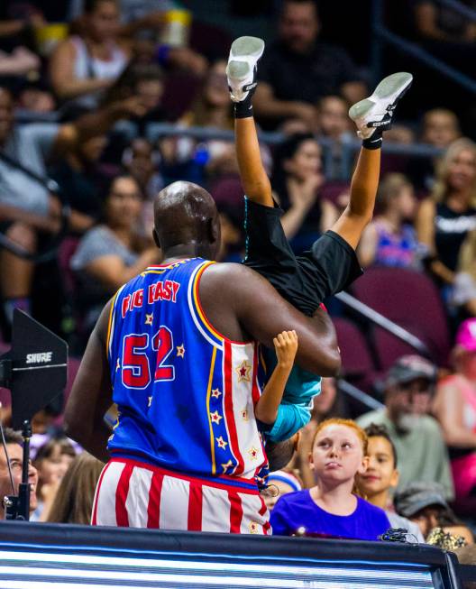 Harlem Globetrotter Big Easy Lofton (52) carries a young fan to his parents while joking around ...