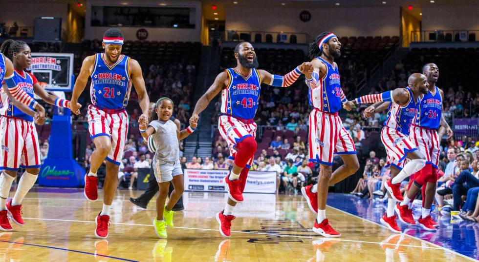 Harlem Globetrotters skip onto the court with a young fan Gianna Burney, 6, on a timeout as the ...