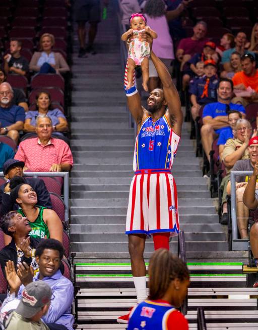 Harlem Globetrotter Bulldog Mack (5) holds up Kaia Johnson, 4 months old, in a parody of "The L ...