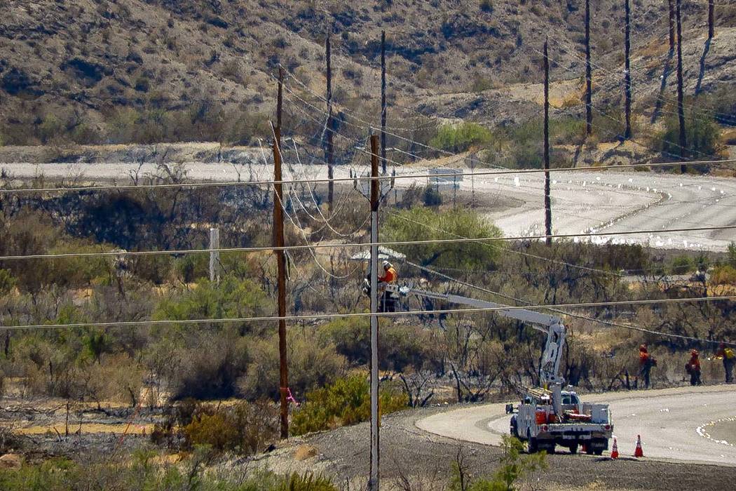 Crews make repairs to power lines in a burned area from the fire at Big Bend of the Colorado St ...