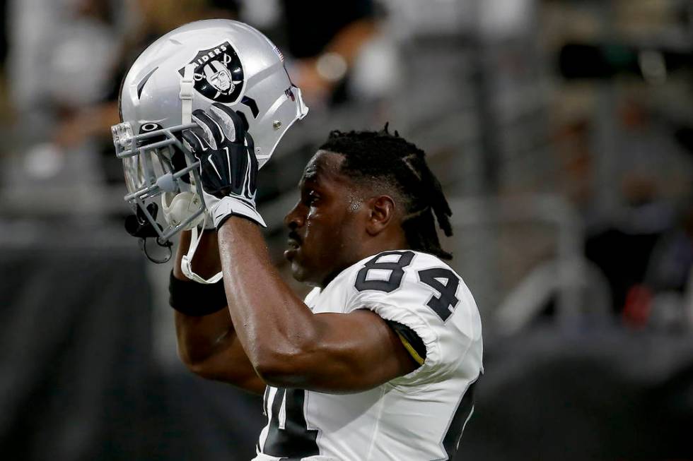 Oakland Raiders wide receiver Antonio Brown (84) puts on his helmet prior to an NFL football ga ...