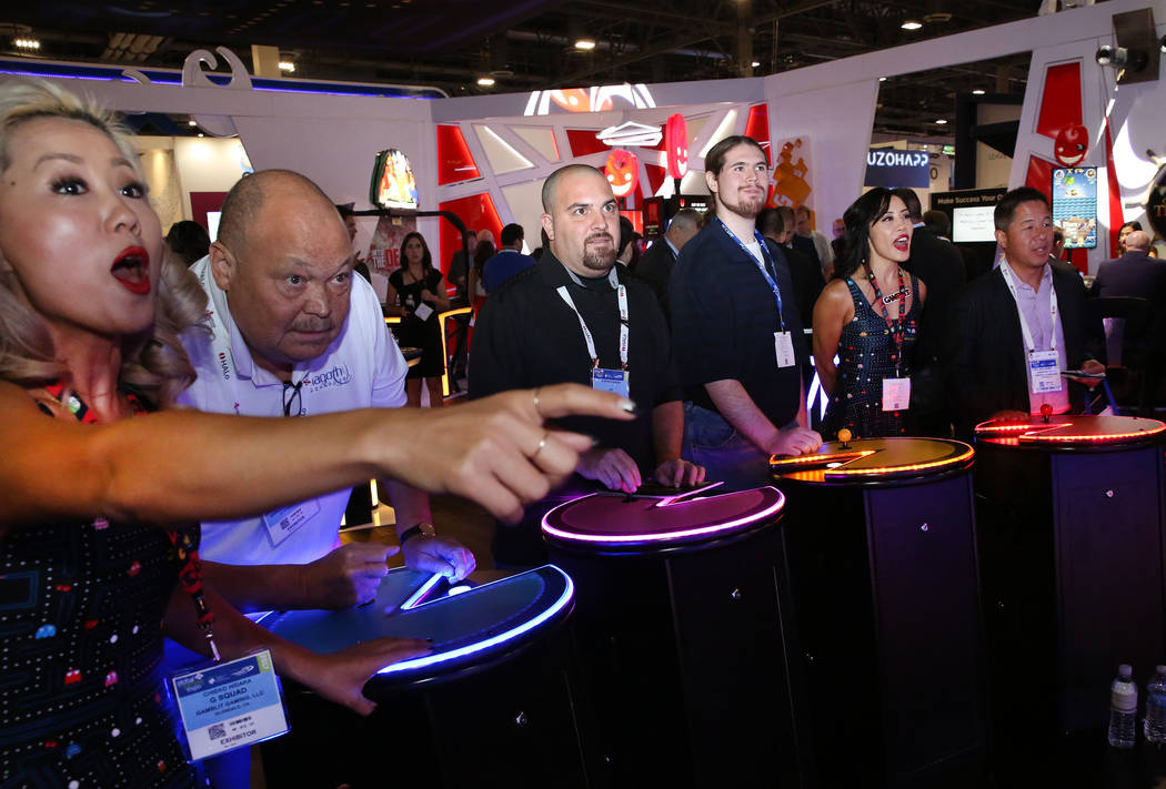 Chieko Hidaka, left, of Gamblit Gaming, reacts as expo goers, including Mike Davis, second left ...