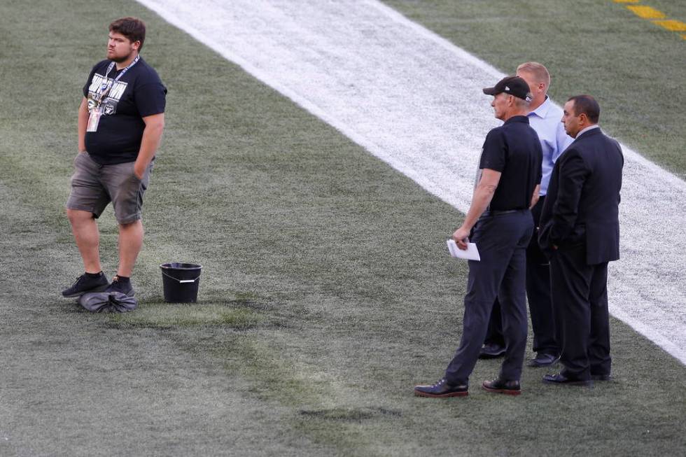 Officials assess the location where the CFL goal post holes were, before an NFL preseason footb ...