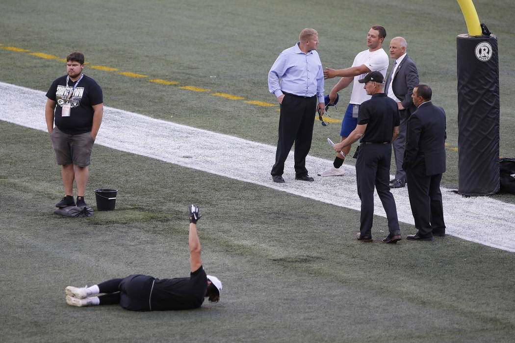 Officials assess the location where the CFL goal post holes were, before an NFL preseason footb ...