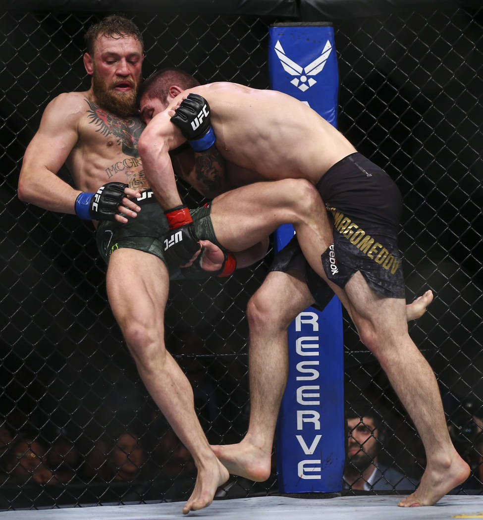 Khabib Nurmagomedov brings Conor McGregor to the mat during their lightweight title bout at UFC ...