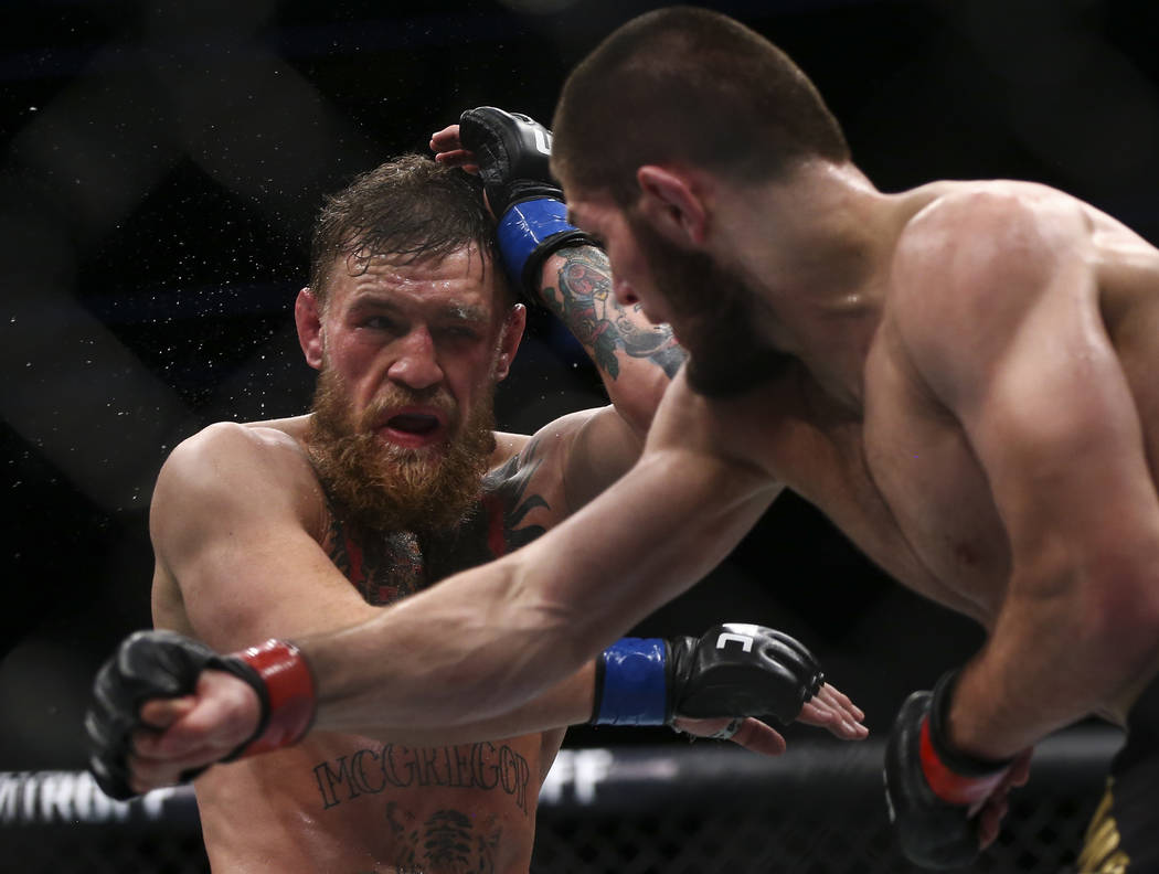 Conor McGregor, left, takes a hit from Khabib Nurmagomedov during their lightweight title bout ...