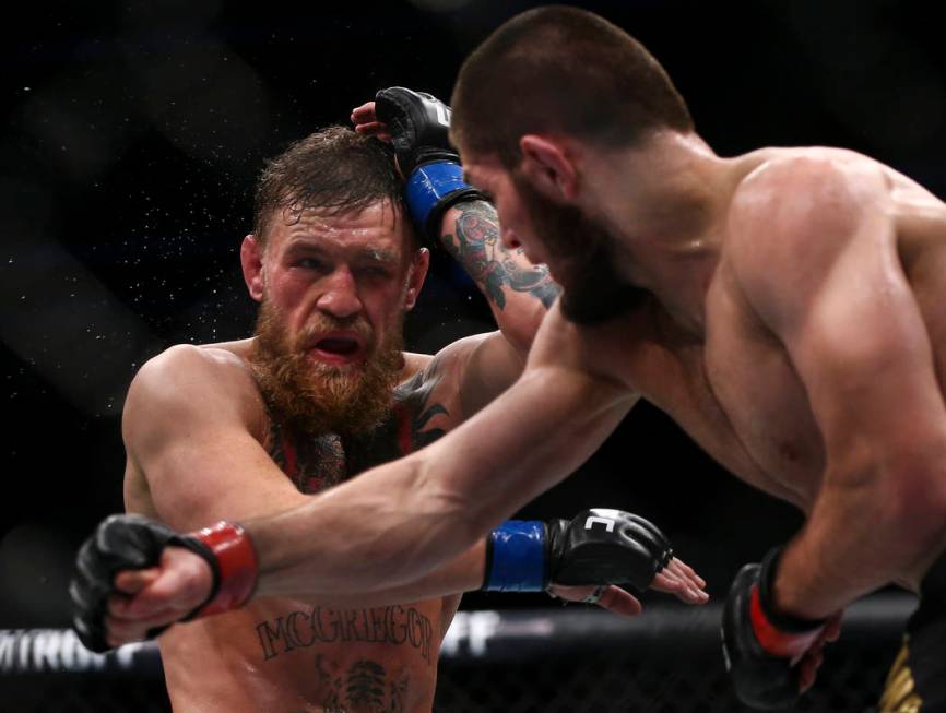 Conor McGregor, left, takes a hit from Khabib Nurmagomedov during their lightweight title bout ...