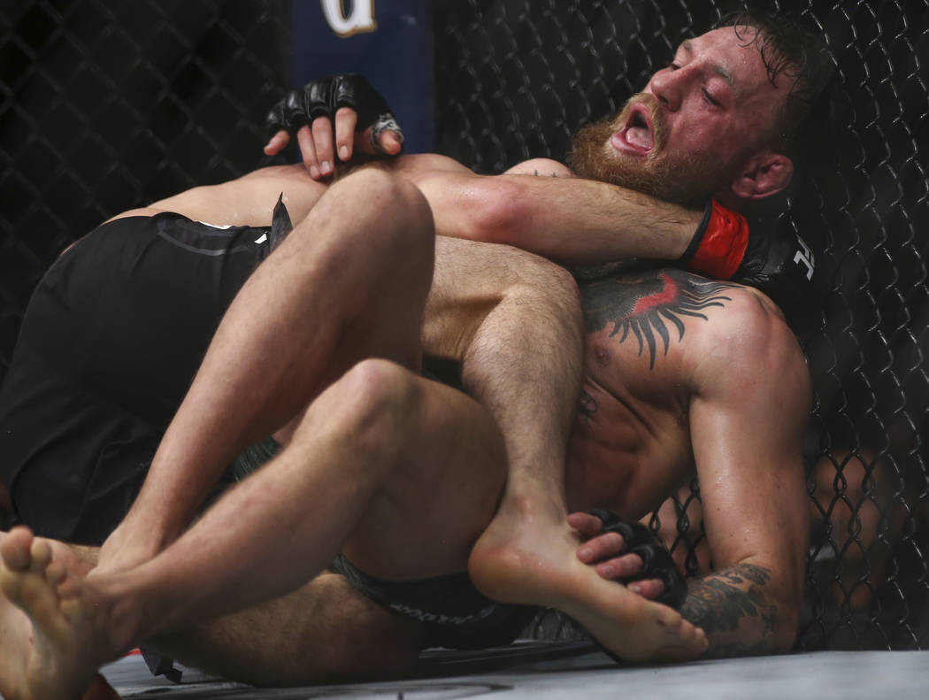 Khabib Nurmagomedov keeps Conor McGregor down on the mat during their lightweight title bout at ...