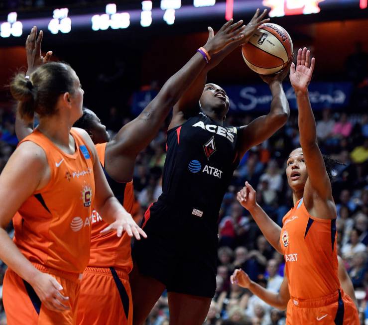 Las Vegas Aces guard Jackie Young scores between Connecticut Sun forwards Shekinna Stricklen, b ...