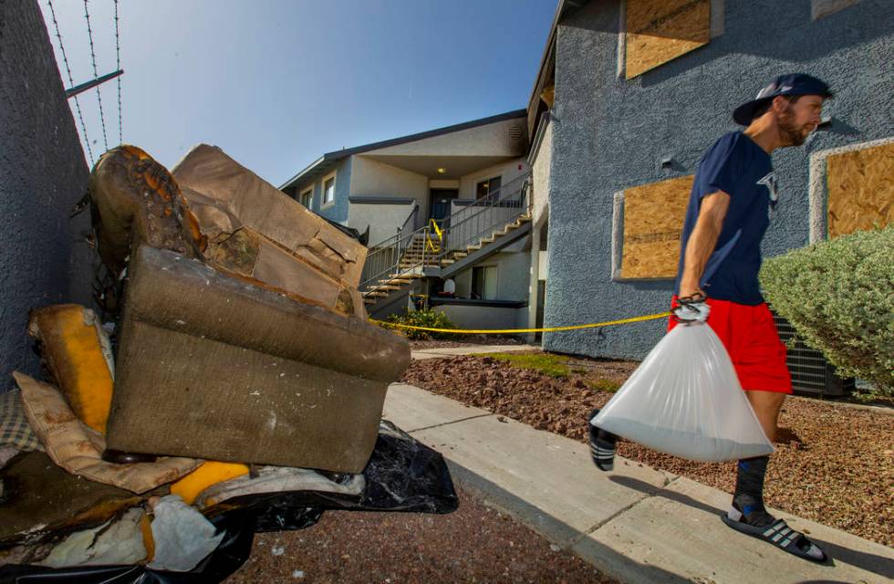 A neighbor passes by the burnt remains outside from an early morning fire at The Bristol at Sun ...