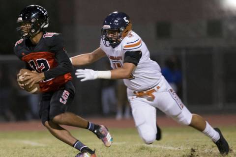 Las Vegas sophomore quarterback Ja'Shawn Scroggins (12) scrambles past Legacy junior linebacker ...