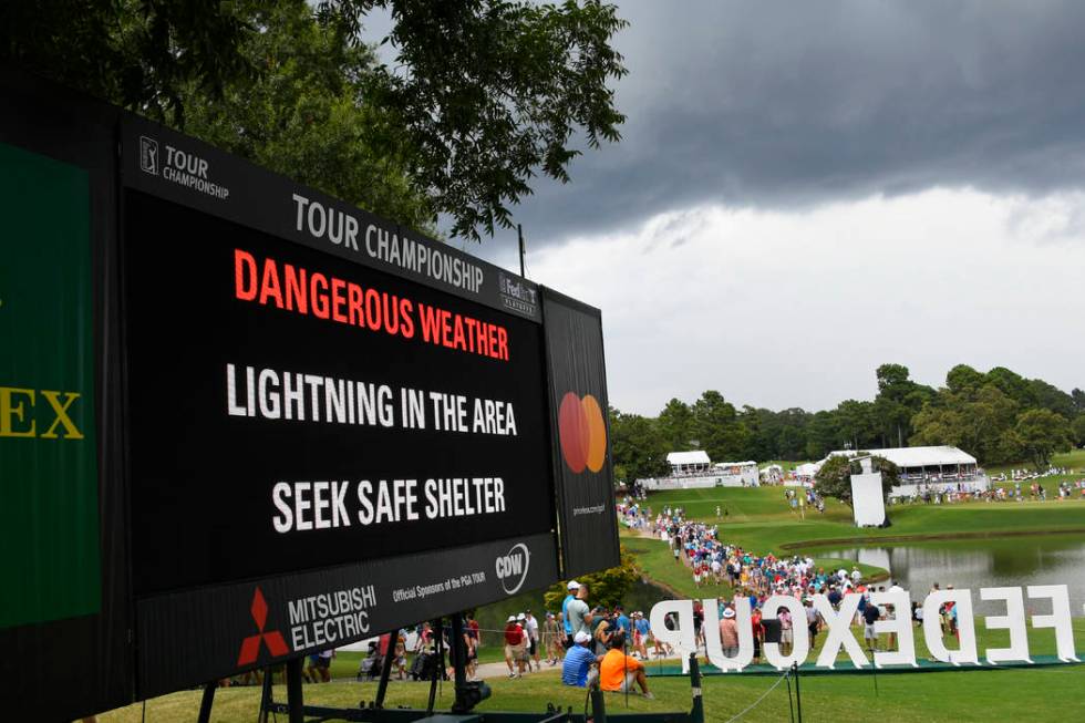 A sign warns of inclement weather as fans come off the course after a delay was called during t ...