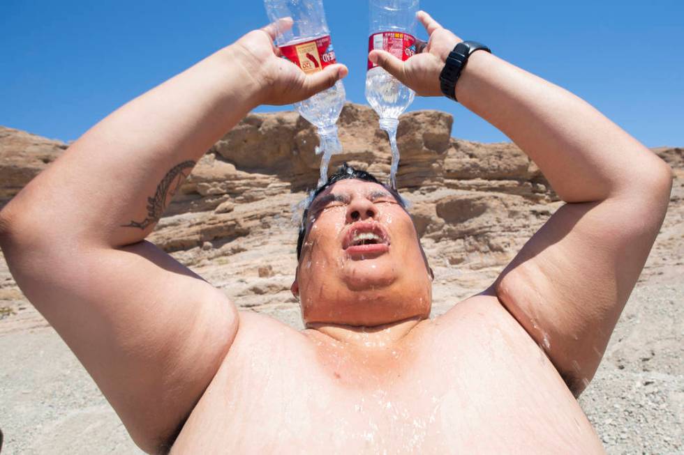 Omar Ramirez, 29, bathes with two water bottles during a hot summer day in the sun after pickin ...