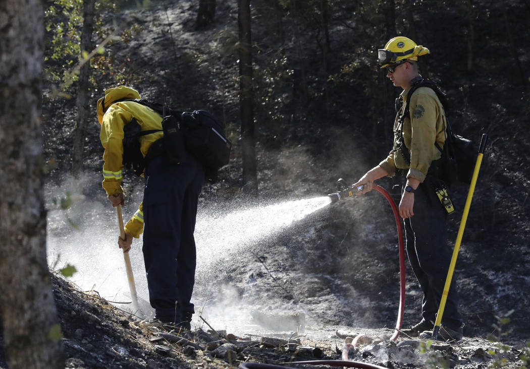 Firefighters from the Marin County Fire Department put out hot spots Friday, Aug. 23, 2019, a d ...