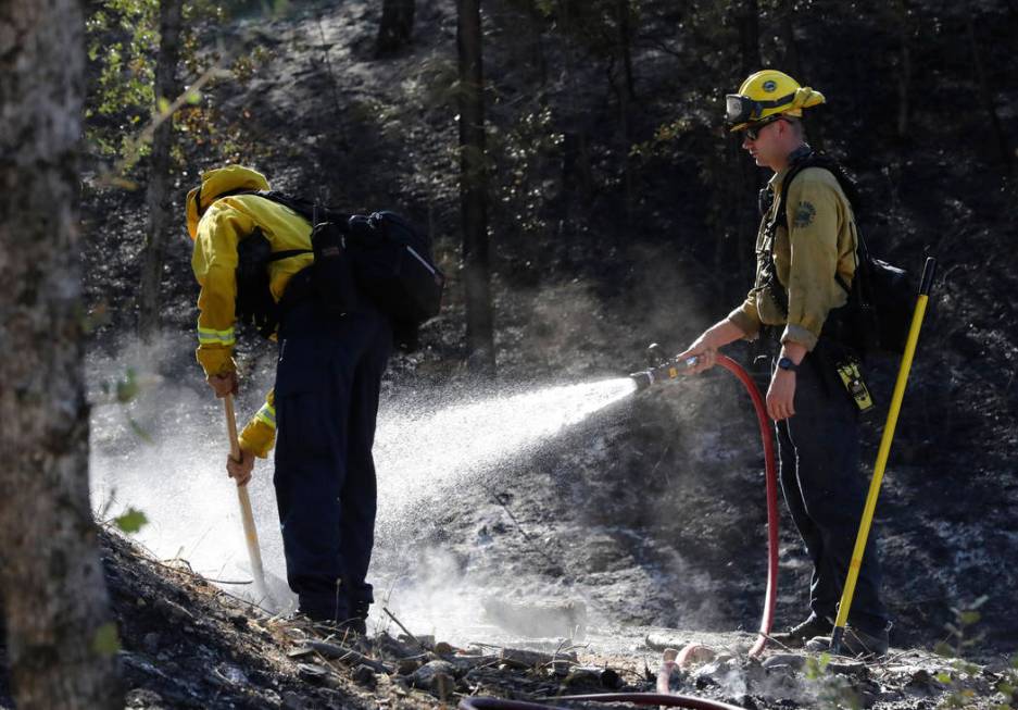 Firefighters from the Marin County Fire Department put out hot spots Friday, Aug. 23, 2019, a d ...