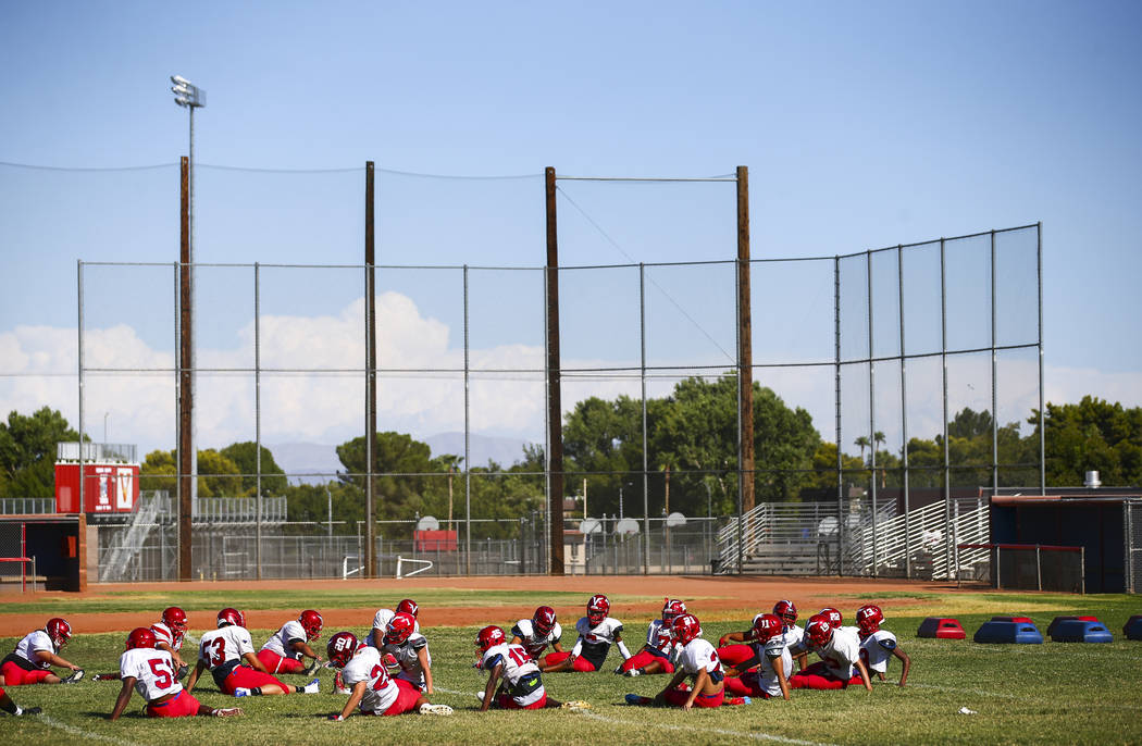 Players stretch and warm up during football practice at the baseball field at Valley High Schoo ...