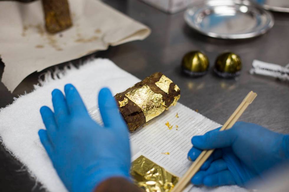 Executive Chef Zhen Han prepares The Gold Encrusted Filet Mignon by covering the meat with shee ...