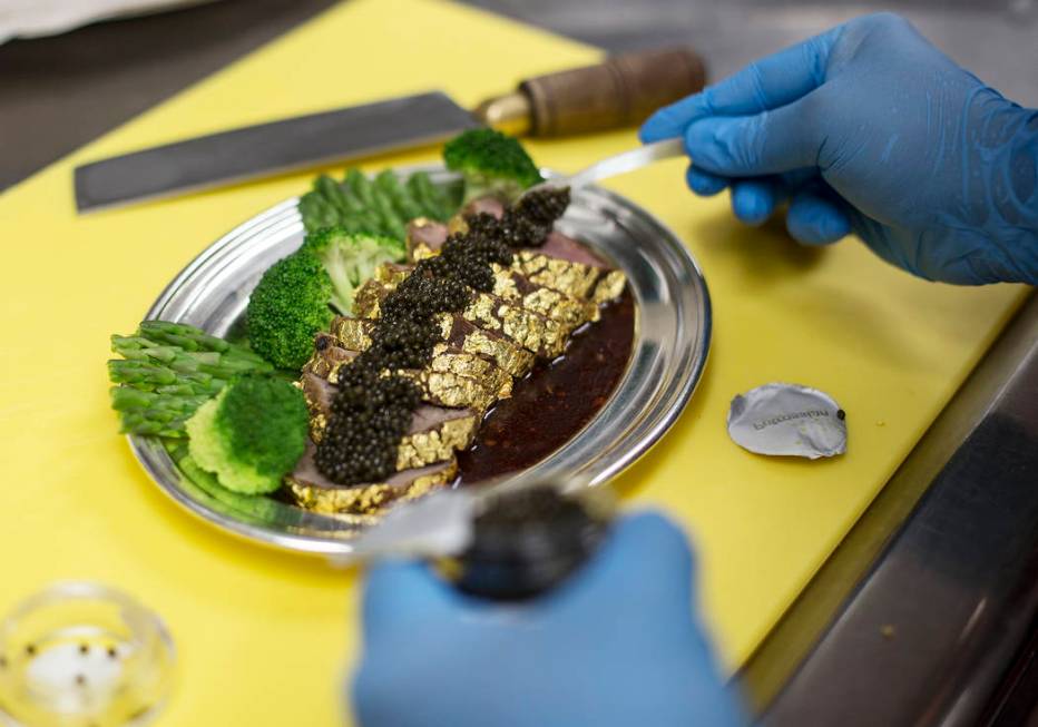 Executive Chef Zhen Han prepares The Gold Encrusted Filet Mignon by adding Petrossian Tsar Impe ...