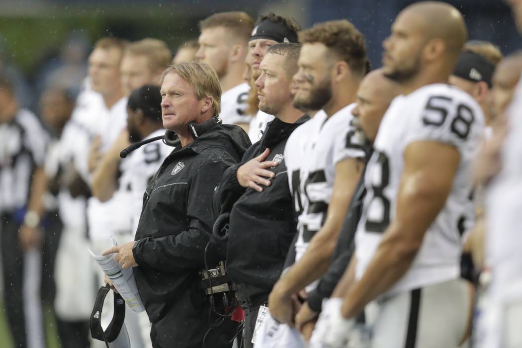 Oakland Raiders head coach Jon Gruden, center, stands with his players during the singing of th ...