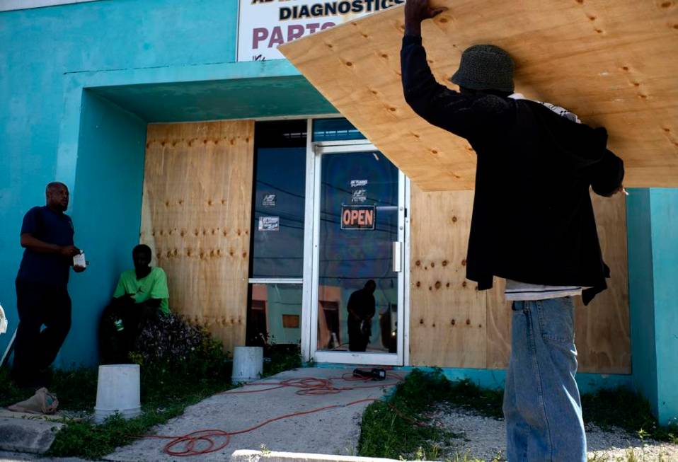 Workers board up a shop’s window front as they make preparations for the arrival of Hurr ...