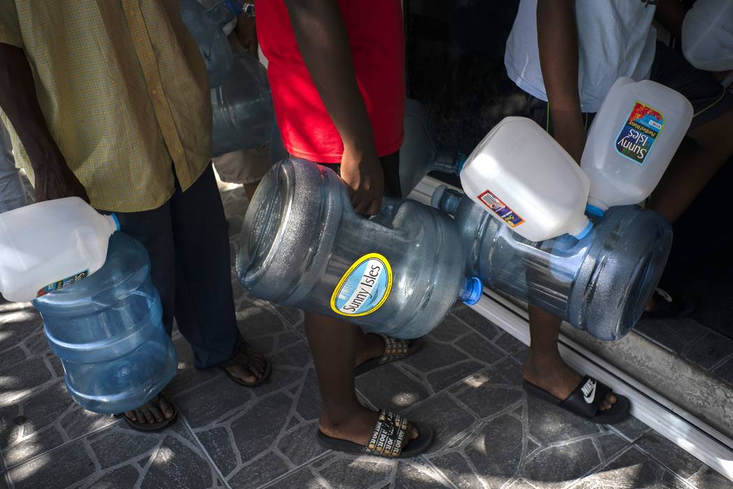 People line up to buy water at a store before the arrival of Hurricane Dorian, in Freeport, Bah ...
