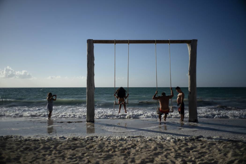 Tourists swing on the beach before the arrival of Hurricane Dorian, in Freeport, Bahamas, Frida ...