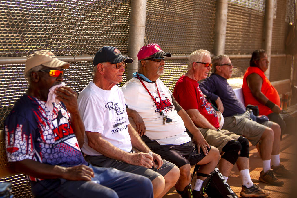 Members of the Las Vegas Senior Softball Association watch the inning of a play during a baseba ...