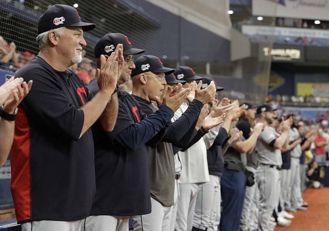 Cleveland Indians players and coaches applaud as pitcher Carlos Carrasco warms up during the se ...