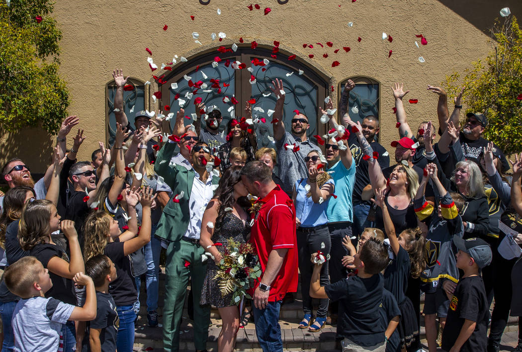 Guests toss flower petals as Laura and Justin Long kiss beside Vegas Golden Knights player Ryan ...