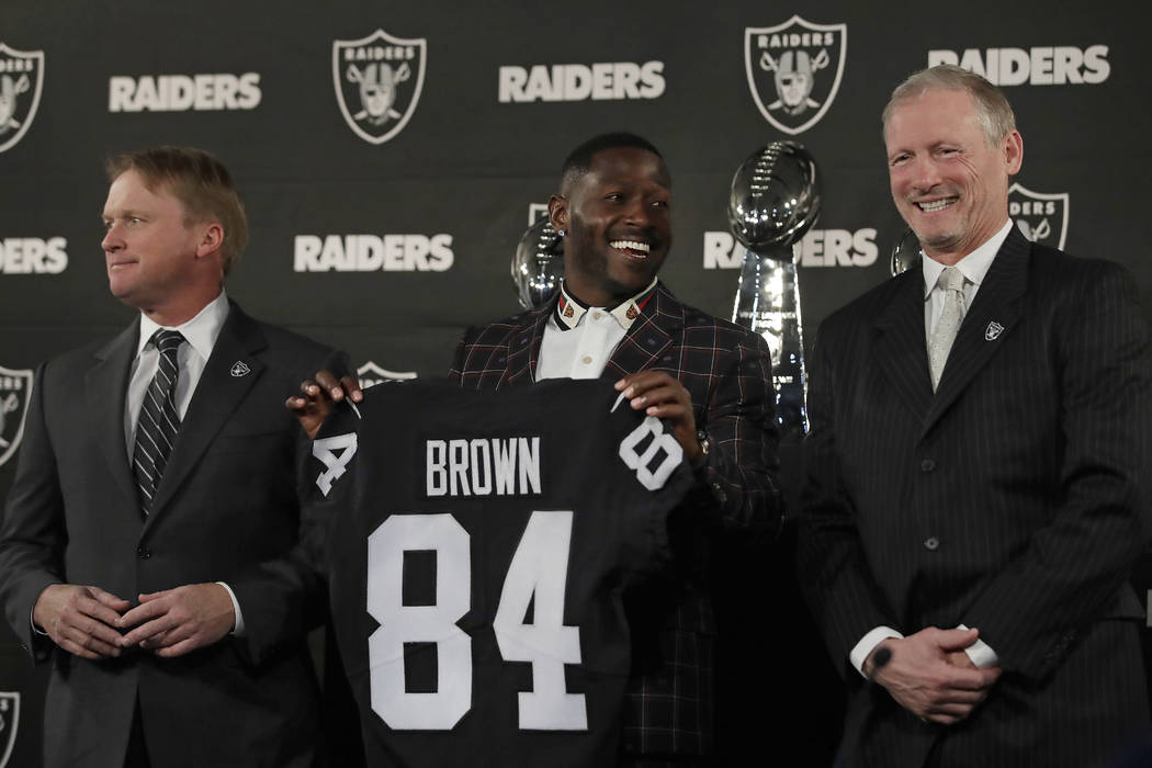 Oakland Raiders wide receiver Antonio Brown, center, holds his jersey beside coach Jon Gruden, ...