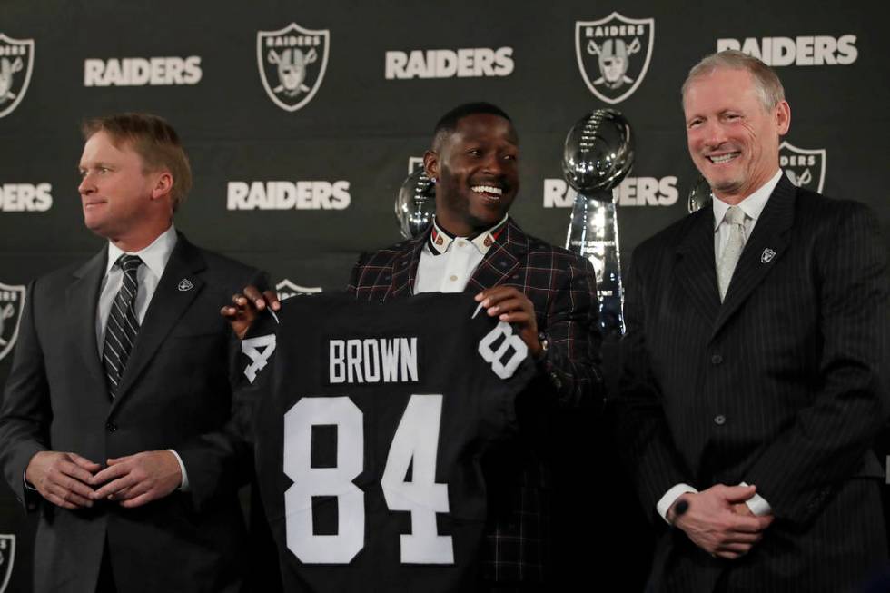 Oakland Raiders wide receiver Antonio Brown, center, holds his jersey beside coach Jon Gruden, ...