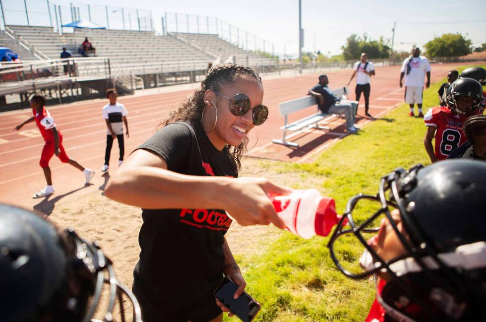 Alvina Conway, left, supplies water for TMT Red Lions player Anthony Rebel, right, and other p ...
