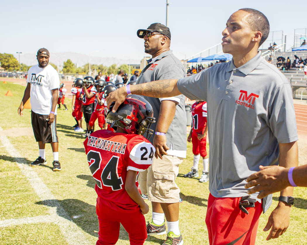 Devin Conway pats the helmet of TMT Red Lion player Justice Banks, 8, during a youth football g ...