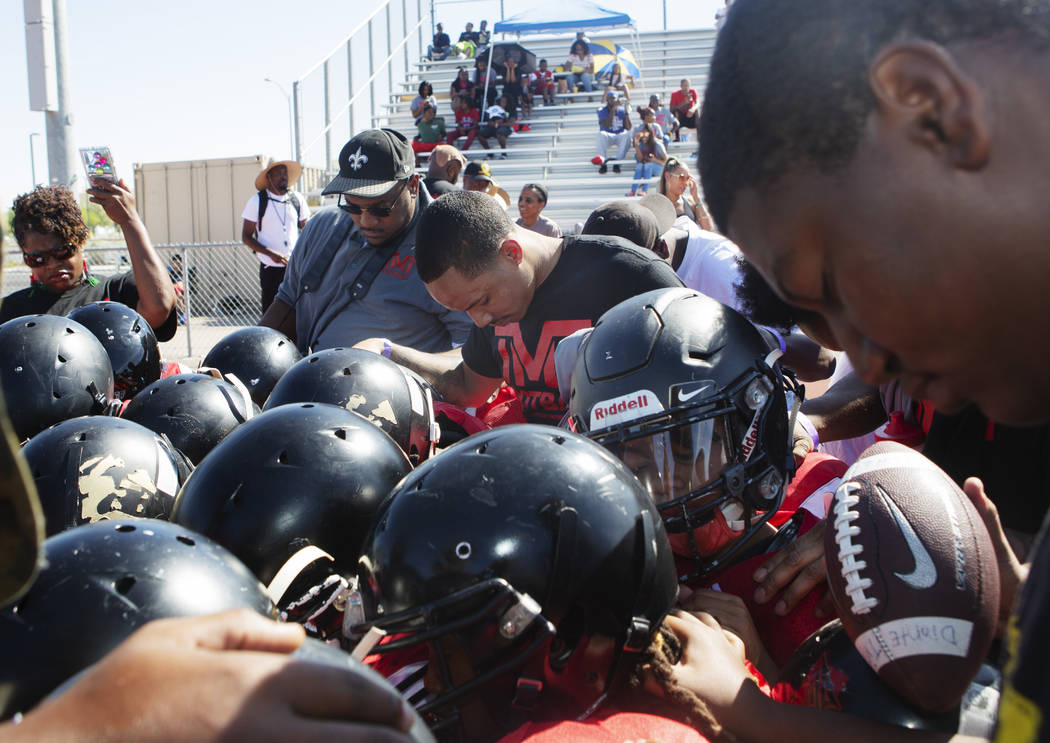 Devin Conway, center, prays with TMT Red Lions players and coaches at Bonanza High School on Sa ...