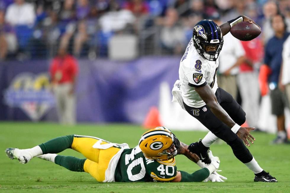 Baltimore Ravens quarterback Lamar Jackson, right, avoids a hit fromGreen Bay Packers linebacke ...