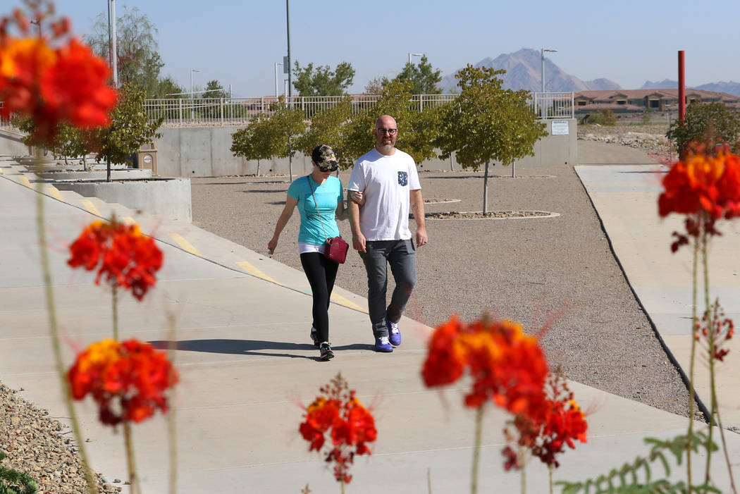 Adam Gnesia and his wife, who declined to give her name, both of Henderson, walk during a sunny ...