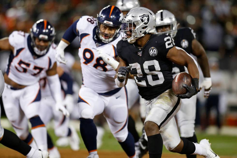 Oakland Raiders running back Josh Jacobs runs with the ball as Denver Broncos defensive end DeM ...