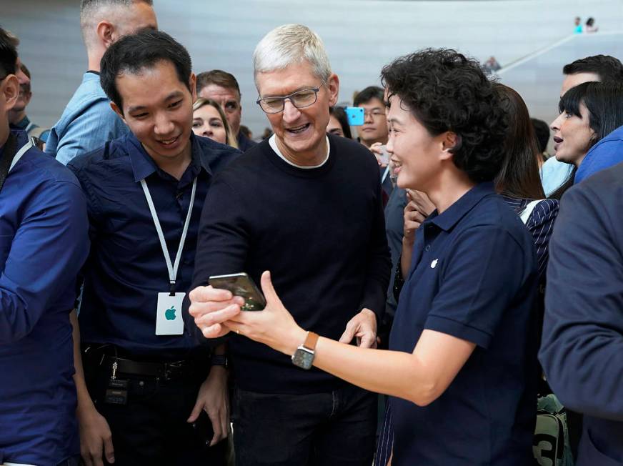 Apple CEO Tim Cook, center, looks at the the new iPhone 11 Pro Max, during an event to announce ...