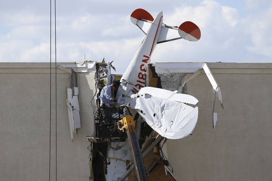 A worker pulls debris off a single engine plane prior to removal after it crashed into the term ...
