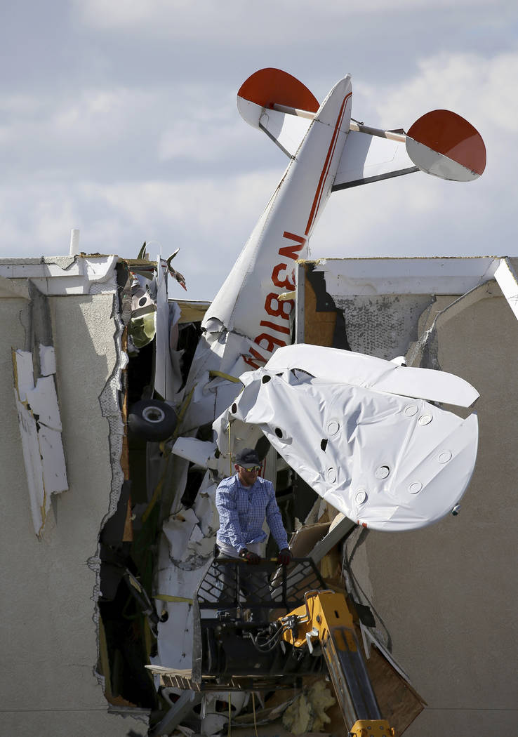 A worker moves around a single-engine plane prior to removal after it crashed into the terminal ...